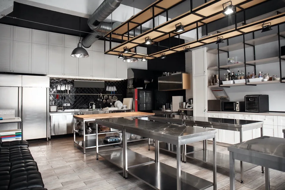 Cuisine professionnelle équipée de tables de travail inox, d'armoires réfrigérées et d'étagères murales